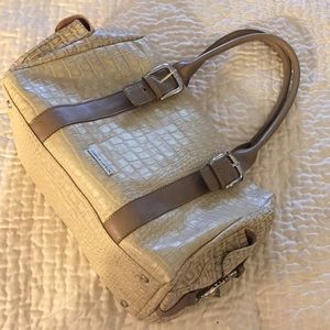 Embossed cream leather bag with tan accents.